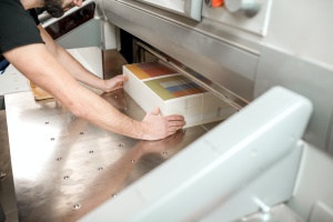 man lining up a stack of paper for cutting at a Bulk Commercial Printing