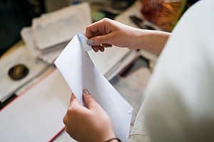 an individual opening a custom envelope to read a letter