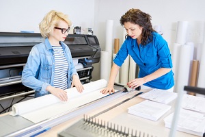 two modern young women working in printing shop looking at commercial printing company