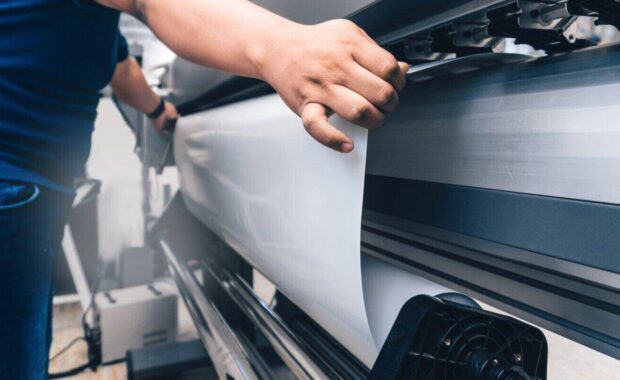 man inserting sheet in large format printer