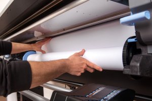 Man adjusting paper in wide format printer