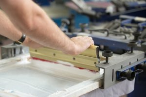 Man applying dye in screen printer