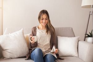 A beautiful woman joyfully reading a magazine while sitting on a sofa