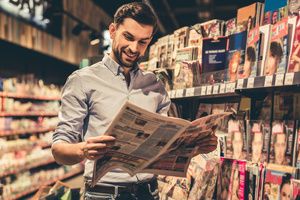 A man reading a newspaper inside a magazine store