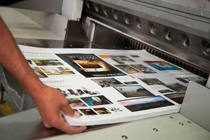 A hand placing a bulk prints in a printer