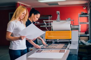 Two women checking the printing process of business brochures